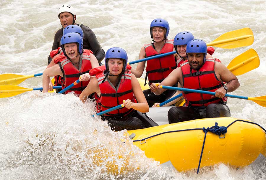 A group of people white water rafting in a river.